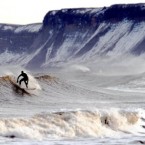 A surfer in high seas with snow covered cliffs in the background in Scarborough.

John Giles/PA Archive/Press Association Images