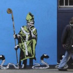 The artist known as ADW leaves his mark on a Dublin city wall. It depicts snakes of a particularly modern species - corruption, white collar crooks, gangland and, er, Michael Flatley - sneaking past a sleeping St Patrick. Pic: Niall Carson/PA Images.