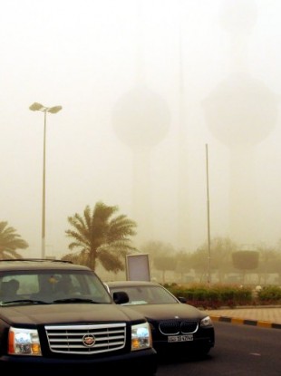 Motorists drive by the Kuwait Towers, nearly invisible in the background at just 300 meters during a severe sandstorm today.