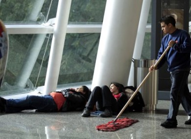 Two women rest as a man wipes the floor at Jorge newbery Airport in Buenos Aires, Argentina.