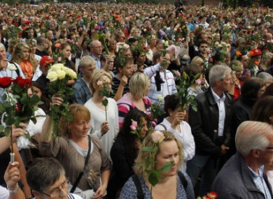 People hold up flowers during a vigil for the victims of the two attacks on Friday.