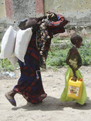 A Somali woman and her child carry food aid distributed by the Muslim Aid Organisation on 4 August 2011.