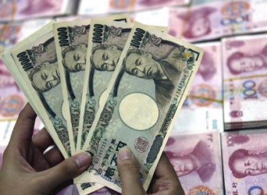 A bank clerk counts Japanese Yen banknotes over RMB (renminbi) yuan banknotes.