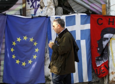 A pedestrian passes by flags for sale in Athens last year