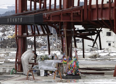 Men offer prayers in front of what's left of the disaster control center in the area devastated by the March 11, 2011 earthquake and tsunami,
