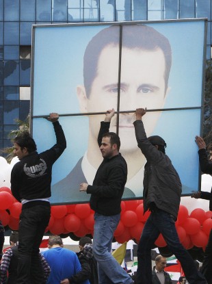 Pro-regime protesters carry a poster of Syrian President Bashar Assad during a rally in Damascus earlier today.