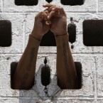 A prisoner rests his arms in the wall of his cell during a Mass for prisoners in the courtyard of La Esperanza penal center in San Salvador, El Salvador, Monday, May 7, 2012. The prisoners asked for Monsignor Fabio Colindres to hold a Mass for them at the prison. (AP Photo/Luis Romero)