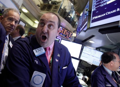 Specialist Peter Giacchi, centre, calls out prices as he works at the post that handles JP Morgan on the floor of the New York Stock Exchange on Friday after the losses were announced.