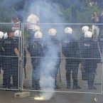 A flare burns behind police officers prior to the Euro 2012 soccer championship Group A match between Poland and Russia in Warsaw, Poland, Tuesday, June 12, 2012. Russian soccer fans clashed with police and Poland supporters in separate incidents in Warsaw on Tuesday, just hours before the two teams were to meet in an emotionally charged European Championship match. Several people were injured. (AP Photo/Alik Keplicz)