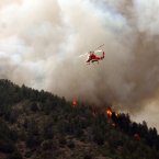 A helicopter tries to slow it down before it left a trail of destruction, burning homes and buildings in it's path. (AP Photo/Bryan Oller/PA)