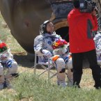 (Left to right) Astronauts Liu Wang, Jing Haipeng and Liu Yang sit in chairs after coming out of the re-entry capsule (Photo by tonglaga/Chinafotopress)
