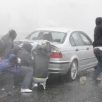 Nationalist rioters use a car as a shield from a police water cannon (AP Photo/Peter Morrison)