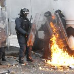 Riot police come under attack from a petrol bomb thrown by nationalist rioters (AP Photo/Peter Morrison)