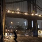 A pedestrian runs through floodwaters in the Dumbo section of the Brooklyn borough of New York, as superstorm Sandy moves through the area, yesterday. Sandy zeroed in on New York's waterfront with fierce rain and winds that shuttered most of the nation's largest city on Monday, darkened the financial district and left a huge crane hanging off a luxury high-rise. (AP Photo/Bebeto Matthews)