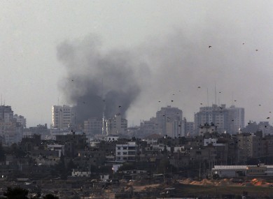 Birds fly as a plume of smoke is seen over central Gaza Strip, after an airstrike by Israeli forces, as seen from the Israel Gaza border on Monday