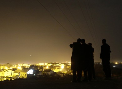 Israelis stand on a hill at the Israeli town of Sderot, background, in southern Israel, overlooking the Gaza Strip last night.