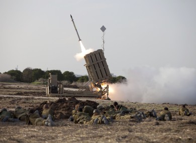 Israeli soldiers lie on the ground as an Iron Dome missile is launched near the city of Ashdod