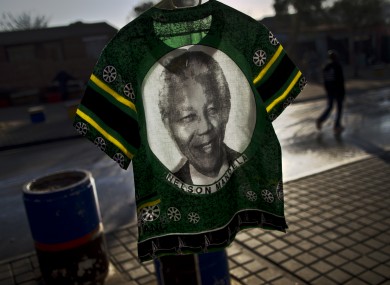 A South African man, right, walks past a T-shirt bearing the image of former South African President Nelson Mandela displayed for sale by a vendor.