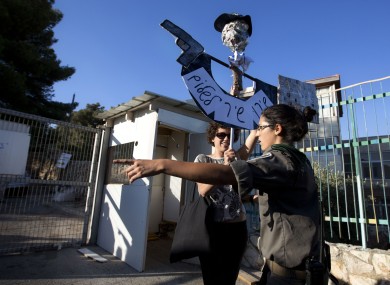 An Israeli border police officer argues with an Israeli left wing activist as she holds a sign to protests during a ceremony to mark the resumption of the construction of housing units in an east Jerusalem neighbourhood.
