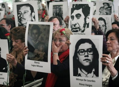 Chile's former President Michelle Bachelet, center, wipes a tear as she stands with her mother Angela Jeria, left, and Margarita Romero, president of the Villa Grimaldi organization, right, all holding photographs of victims of the dictatorship of Gen. Augusto Pinochet