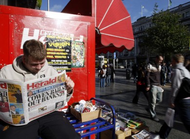 A unidentified person reads the Dublin Evening Herald, which led with the banking crisis in Ireland, on O'Connell Street in Dublin, Ireland, Tuesday, Sept. 30, 2008.