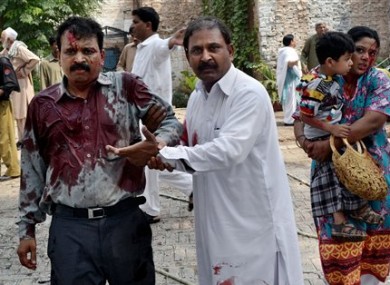 A Pakistani man helps an injured victim of a suicide attack at a church in Peshawar, Pakistan.