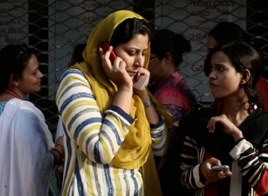 A Pakistani woman speaks on her mobile phone after rushing out of her apartment.