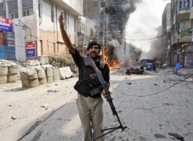 A Pakistani police officer calls for help moments after a car bomb attack in Peshawar.